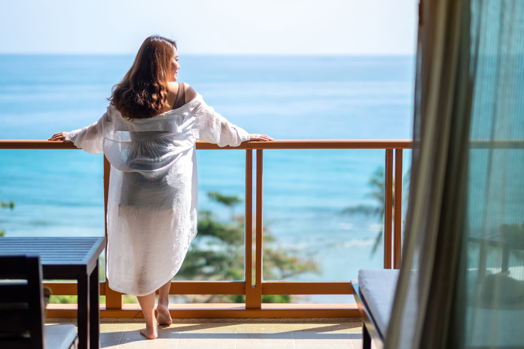 woman enjoying a beach view from her hotel room balcony.